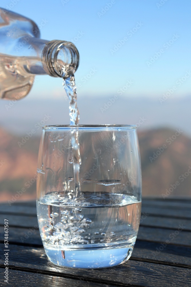 clean and fresh spring drinking Water pouring from the bottle into a ...
