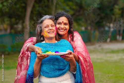 Two Indian woman playing colors at park and celebrating holi festival.