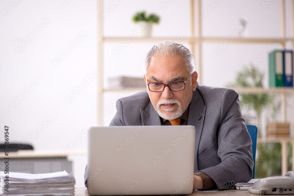Old male employee working at workplace Old male employee working at workplace