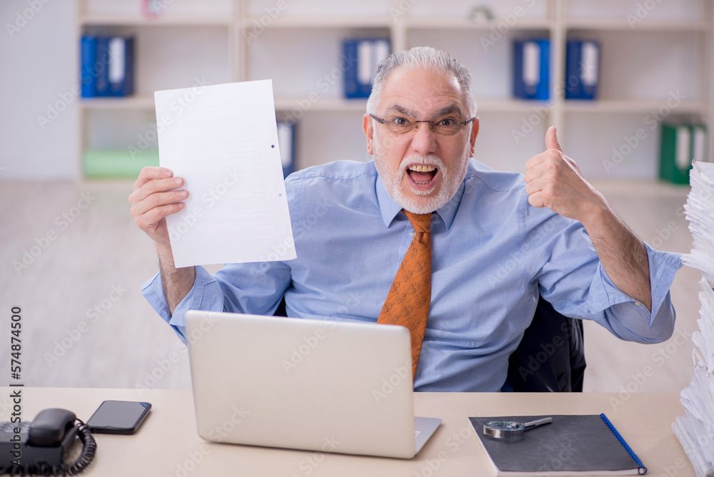 Old male employee unhappy with excessive work in the office Old male employee unhappy with excessive work in the office