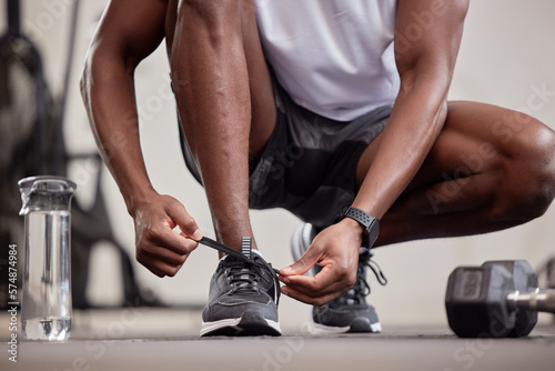 Hands, fitness and tie shoes in gym to start workout, training or exercise practice. Sports, health and black man or athlete tying sneakers to get ready for exercising, running or cardio for wellness