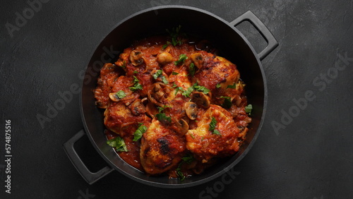 Chicken Chasseur, poulet saute chasseur, chicken stew with mushrooms in a tomato and white wine sauce in black bowl on dark table, French cuisine