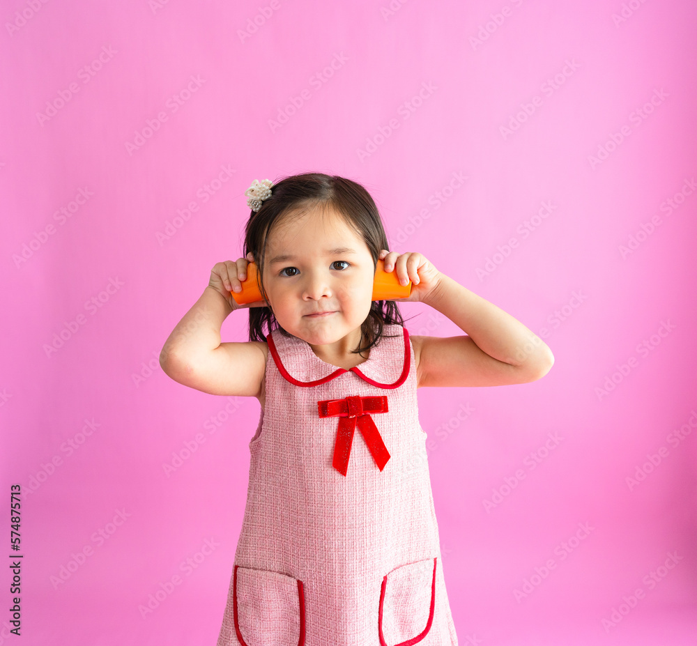 Pretty little girls sitting on floor and holding two orange cups to her ears. Pretty little girls sitting on floor and holding two orange cups to her ears.