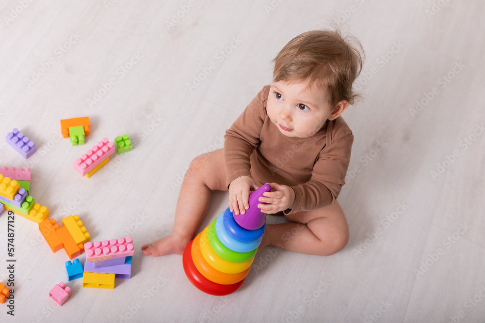 adorable baby in brown shirt playing with toys, card, banner, space for text adorable baby in brown shirt playing with toys, card, banner, space for text