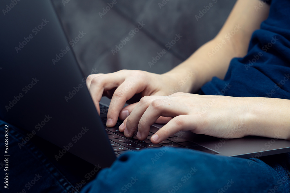 Digital laptop computer on male legs closeup. Young business man typing on keyboard of portable modern notebook.