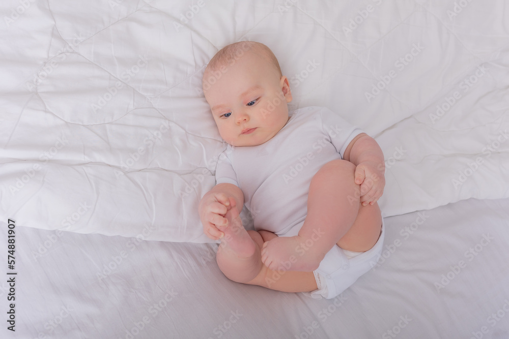 blue-eyed baby in a white bodysuit lies in a crib and looks at the camera blue-eyed baby in a white bodysuit lies in a crib and looks at the camera