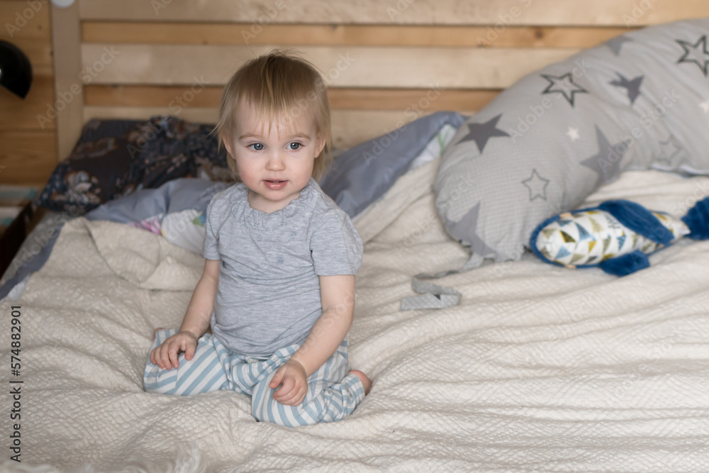 little child sitting on parents bed at home