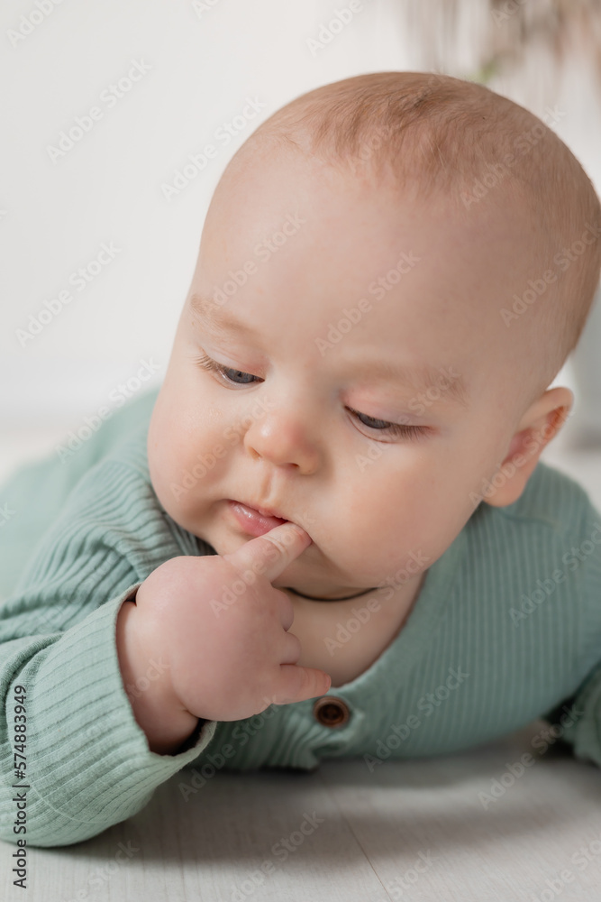 baby in a green jumpsuit learns to crawl on the floor baby in a green jumpsuit learns to crawl on the floor
