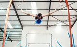 Man, acrobat and gymnast flying off rings in fitness for practice, training or workout at gym. Professional male in gymnastics or performance for athletics, acrobatic or strength and balance exercise