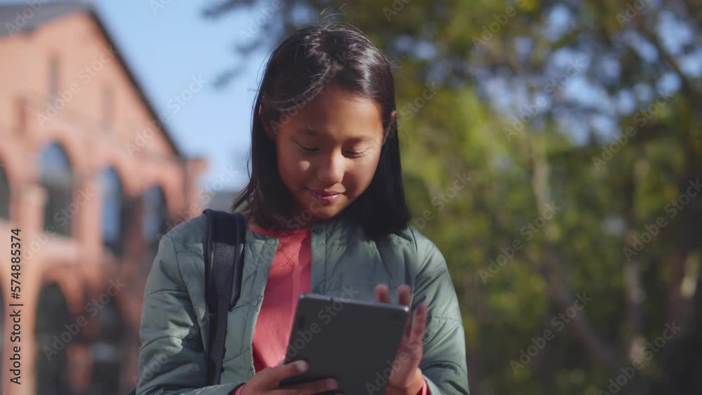 Asian female student using digital tablet outdoors. Realtime Asian female student using digital tablet outdoors. Realtime