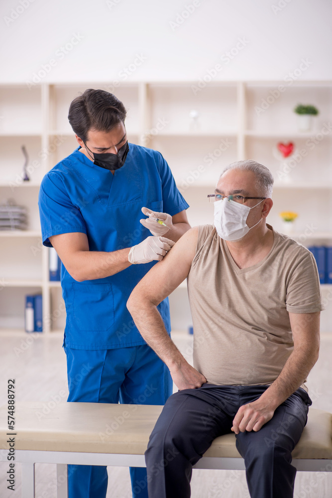 Old male patient visiting young male doctor in vaccination conce Old male patient visiting young male doctor in vaccination conce