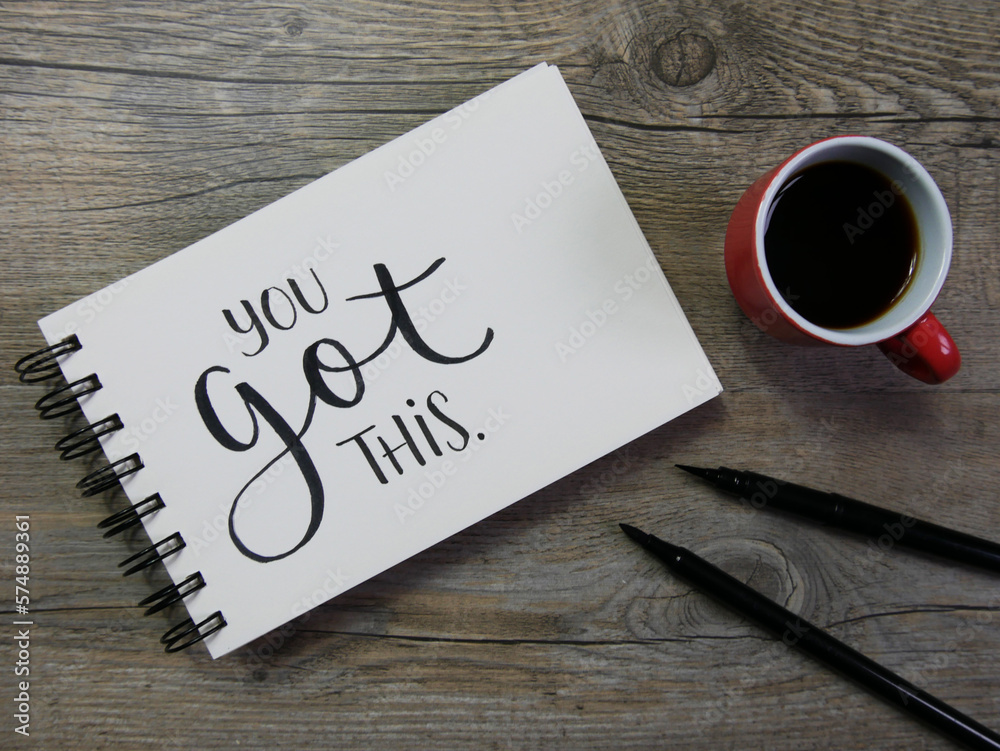 YOU GOT THIS lettering in notebook with cup of coffee and pens YOU GOT THIS lettering in notebook with cup of coffee and pens