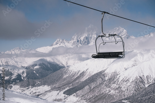 Chair ski lift at ski resort against backdrop of amazing mountain peaks covered with snow