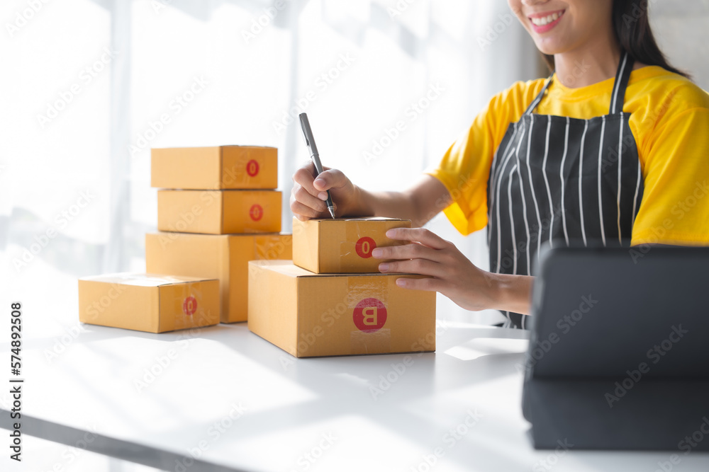 Young pretty asian start up business woman in apron working with online parcel box warehouse selling online product with social media influencer people with subscriber and followers Young pretty asian start up business woman in apron working with online parcel box warehouse selling online product with social media influencer people with subscriber and followers