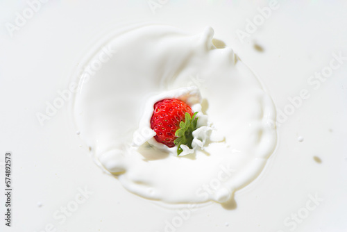 The falling strawberry are splashing into the milk