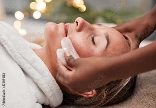 Beauty, gua sha and woman getting a facial massage for wellness, health and self care at a spa. Skincare, cosmetic and calm young female doing a luxury face treatment with rose quartz at a zen salon. photo