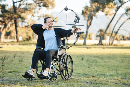 Fototapeta Naklejka Na Ścianę i Meble -  Disabled woman, outdoor archery in wheelchair and challenge with active sports lifestyle in Canada. Person with disability in a park, fitness activity to exercise arms and aim arrow for hobby