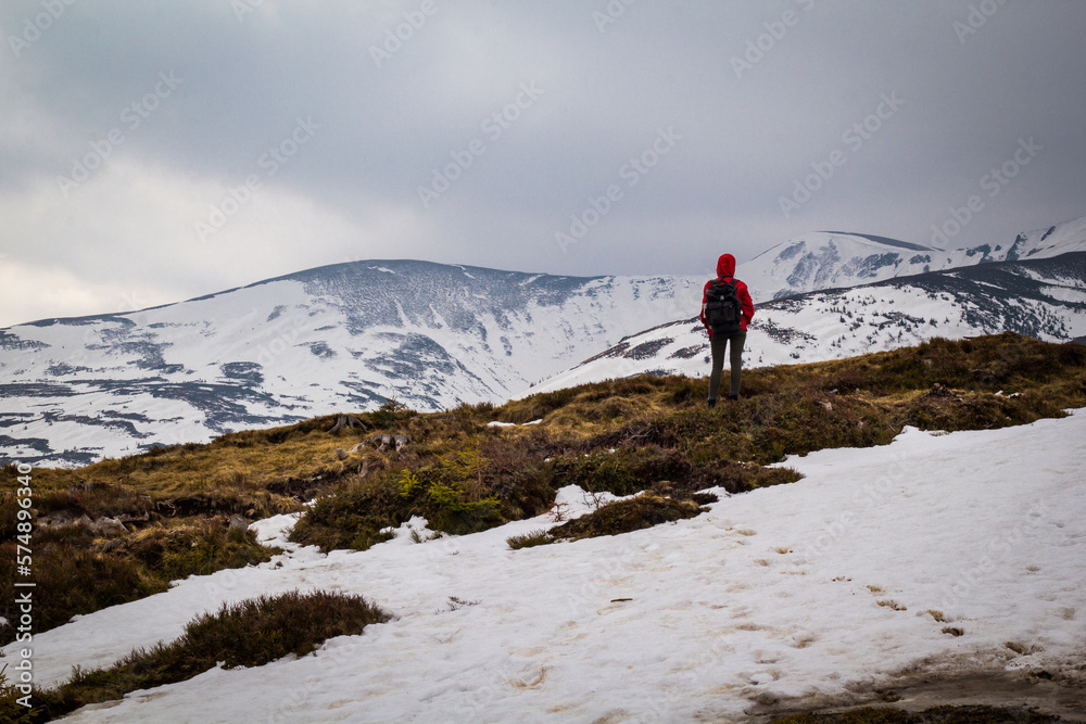 Hiker traveling across snowy mountain slopes landscape photo. Nature scenery photography with gloomy background. Ambient light. High quality picture for wallpaper, travel blog, magazine, article