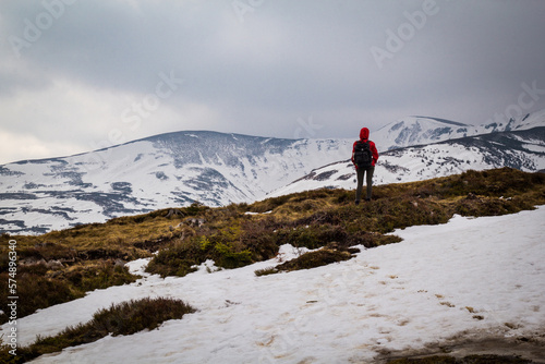 Hiker traveling across snowy mountain slopes landscape photo. Nature scenery photography with gloomy background. Ambient light. High quality picture for wallpaper, travel blog, magazine, article