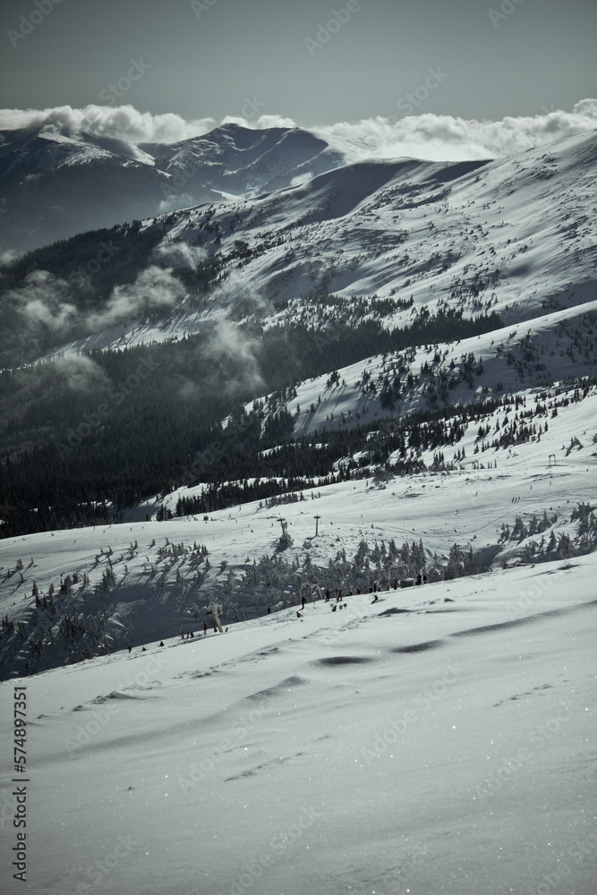 Obraz premium People skiing in ukrainian Carpathian mountains landscape photo. Nature scenery photography with clouds on background. Ambient light. High quality picture for wallpaper, travel blog, magazine, article