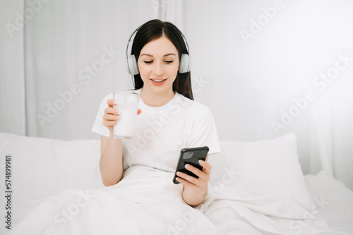 Beautiful woman has woken up on a white bed and holding coffee in the morning at home in morning