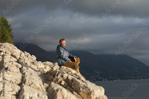 A person on top of a mountain looking at the sea in the evening sun