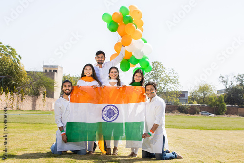 Group of happy young people wearing traditional white dress holding indian flag celebrating Independence day or Republic day. photo