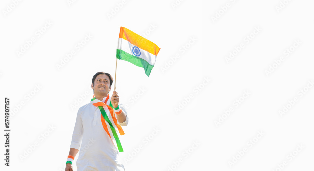happy young man wearing traditional white dress holding indian and weaving flag while standing isolated on white background, celebrating Independence day or Republic day. Low angle shot. happy young man wearing traditional white dress holding indian and weaving flag while standing isolated on white background, celebrating Independence day or Republic day. Low angle shot.