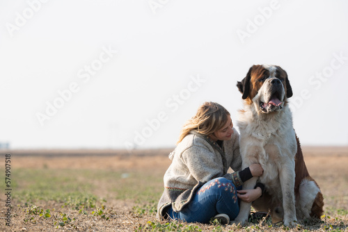 Fototapeta Naklejka Na Ścianę i Meble -  Beautiful girl with blonde hair and her big St. Bernard dog