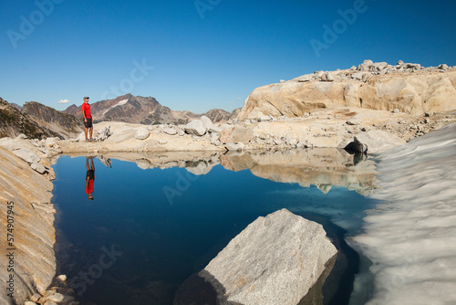 Reflection of a hiker in a glacier fed alpine tarn near Whistler, British Columbia, Canada. photo