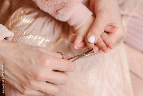 Woman cutting her little daughter s nails