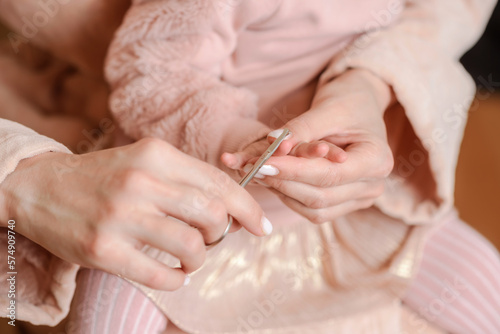 Woman cutting her little daughter's nails