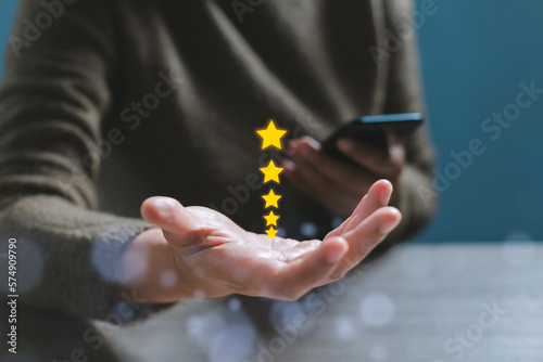 Gesture hand with golden five star awards. Opened hand of customer giving a five star rating. Satisfaction survey, customer service, Success in business concept.
