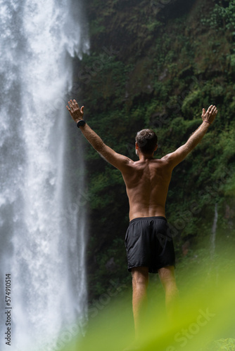 A man, a traveler looks at a waterfall in the jungle, the concep photo