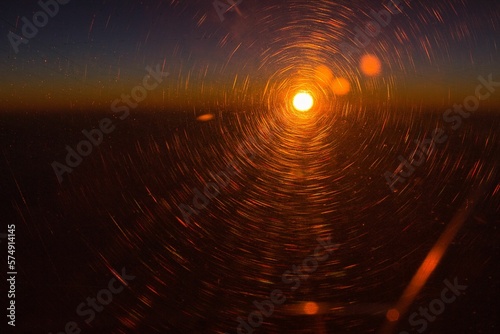 Sunset high above the clouds, taken from an airplane, the sun rays shining in a deep orange and gold colors.