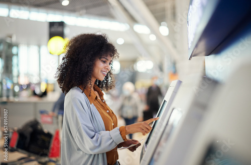 Black woman, airport and smile by self service station for ticket, registration or boarding pass. Happy African female traveler by kiosk machine for travel application, document or booking flight photo