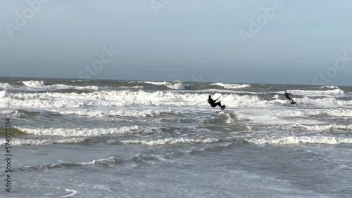 Kite Surfer starting from shoreline with board into ocean waves and jumping into sky - real time