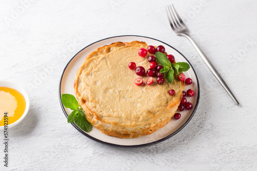 Homemade healthy low calorie cottage cheese casserole with apple served with fresh cranberries, mint, honey and sour cream on a light gray background photo