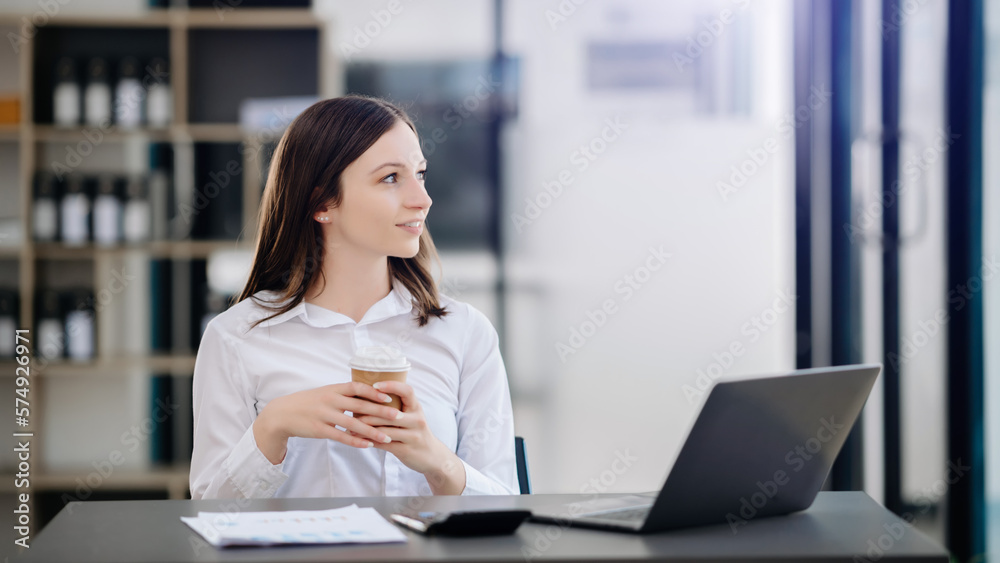 Beautiful Asian woman using laptop and tablet while sitting at her working place. Concentrated at work.