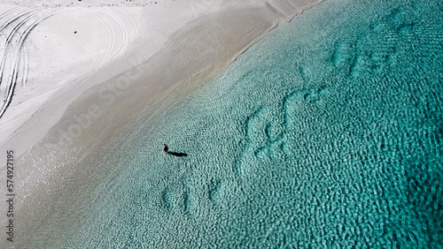 Aerial picture of one person entering the water at the beach in Wylie Bay. Shallow water in Esperance. Beautiful ocean, sand and beach. 1 person and shadow in the shore.  photo
