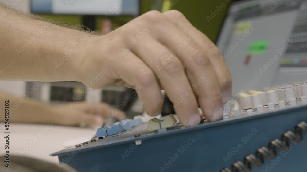 Close up, anonymous audio engineer's hand turning knob on audio mixer in recording studio. Slow motion Close up, anonymous audio engineer's hand turning knob on audio mixer in recording studio. Slow motion