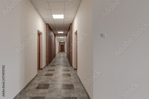 white empty long corridor with red brick walls for room office in interior of modern apartments, office or clinic