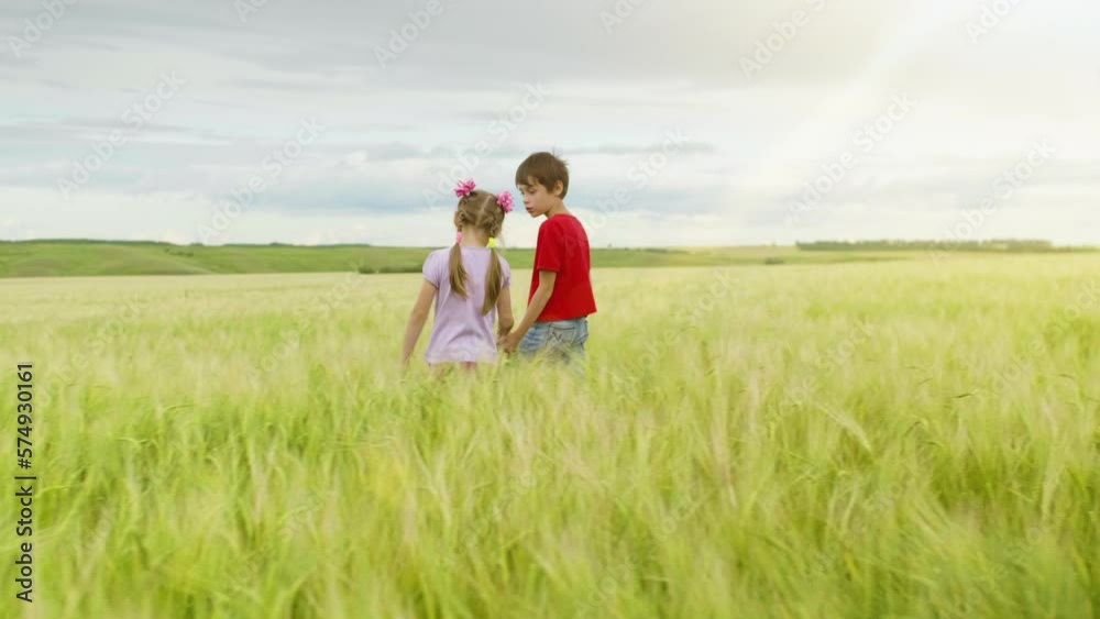 Best Friends Little Boy and Girl are Walking in the Meadow Holding Hands. Little Kids Outdoor. Happy Carefree Childhood. Summertime Best Friends Little Boy and Girl are Walking in the Meadow Holding Hands. Little Kids Outdoor. Happy Carefree Childhood. Summertime