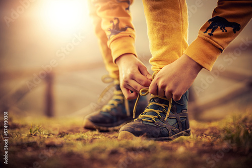 Little boy tying shoelace on his hiking boot photo