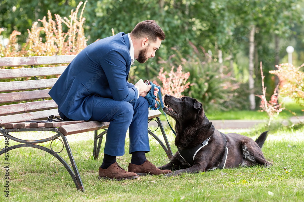 Handsome man in business suit talking to his dog at walk