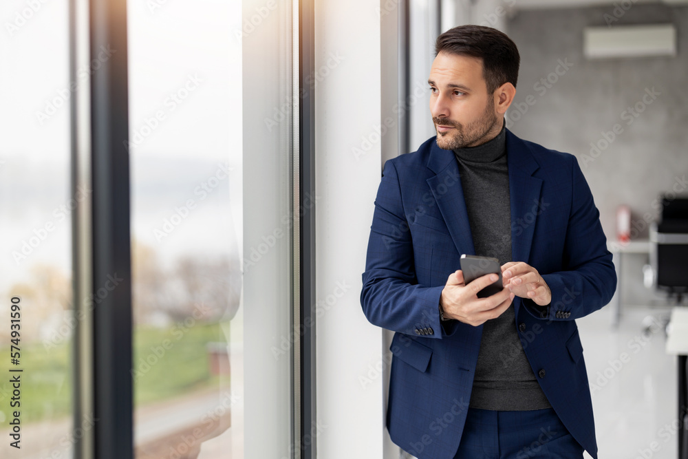 Shot of a young businessman using his phone in the office Shot of a young businessman using his phone in the office