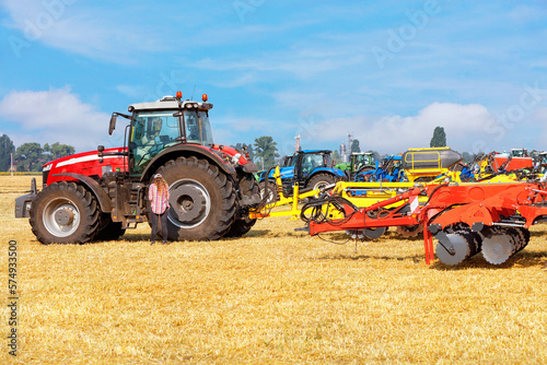 Agricultural machinery at the exhibition  powerful multi-row disc harrow with a tractor against the backdrop of an agricultural field.