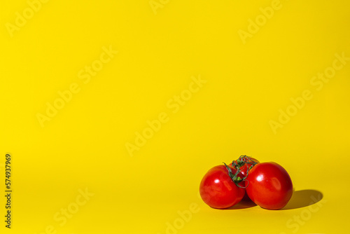 tomatoes vegetables ,three objects,hard shadow,red color round,lie on the surface of the yellow background.concept juice vitamins.