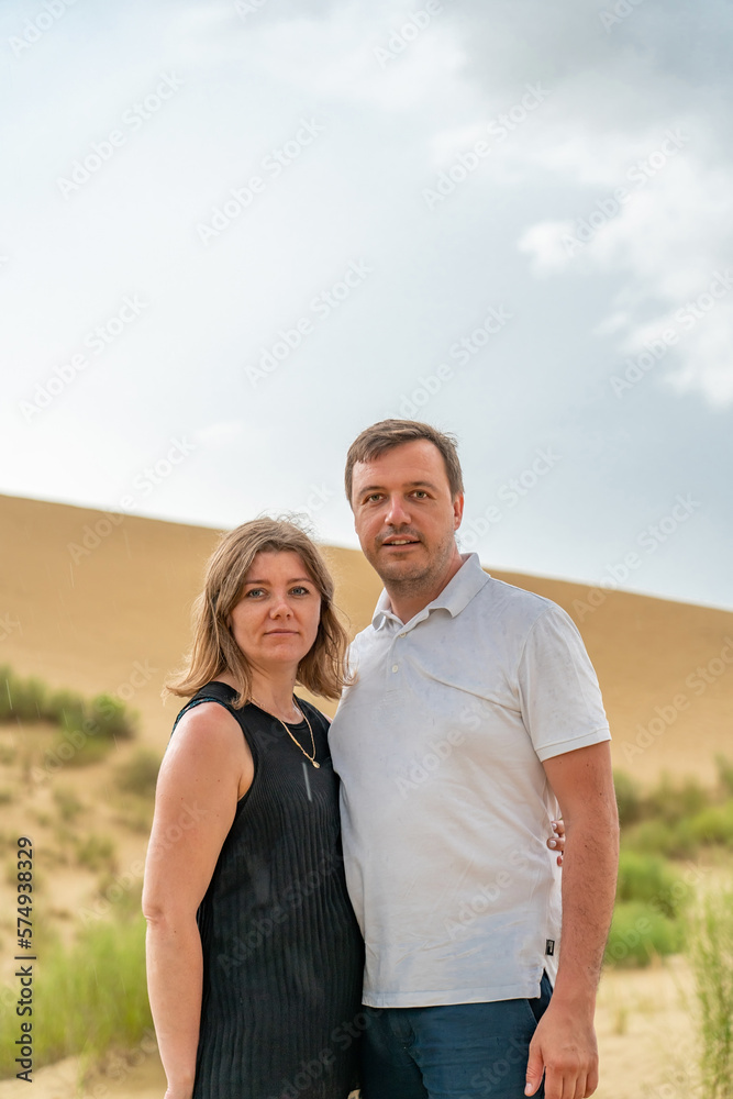 Obraz premium Happy hugging couple on sand dunes looking at camera