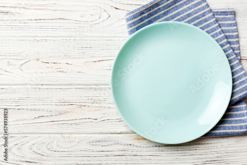 Top view on colored background empty round blue plate on tablecloth for food. Empty dish on napkin with space for your design